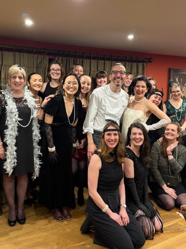 Chef Alpay surrounded by guests in 1920s-style outfits at a themed party