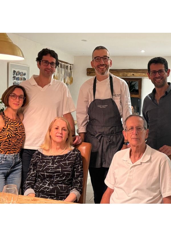 Chef Alpay in his apron with five guests gathered around a dining table