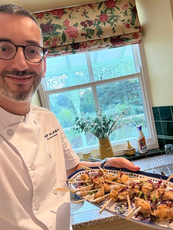 Chef Alpay presenting a colourful platter of canapés in a home kitchen