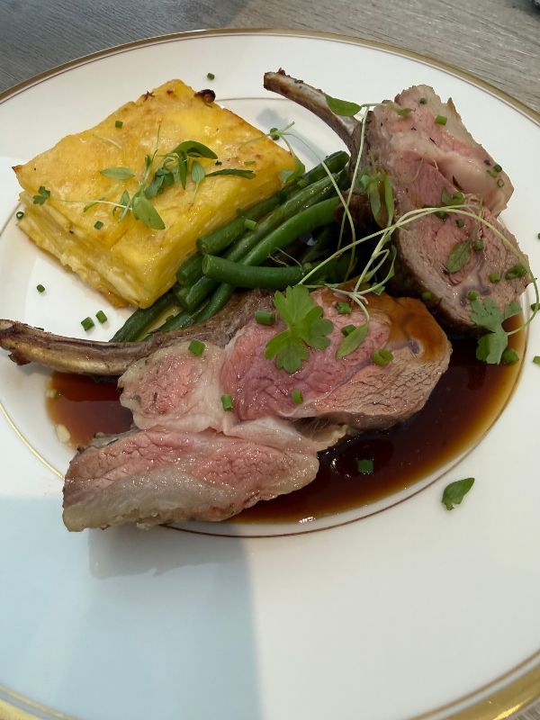 Sliced rack of lamb with layered potatoes, green beans and jus