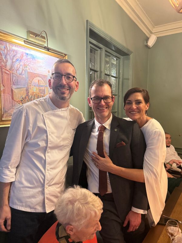 Chef Alpay smiling with two guests at a private dining celebration