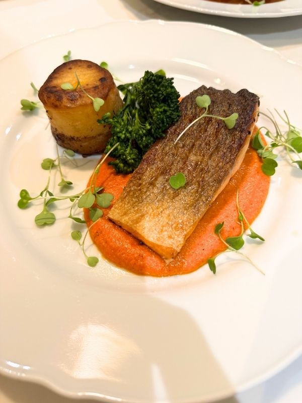 Crisp-skinned salmon fillet with vegetables, potato and a colourful sauce